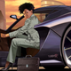 A woman wearing a nice business suit exits a car while looking at the camera.